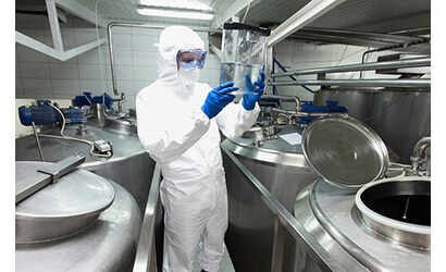 A male in a lab suit looking at a chemical mix
